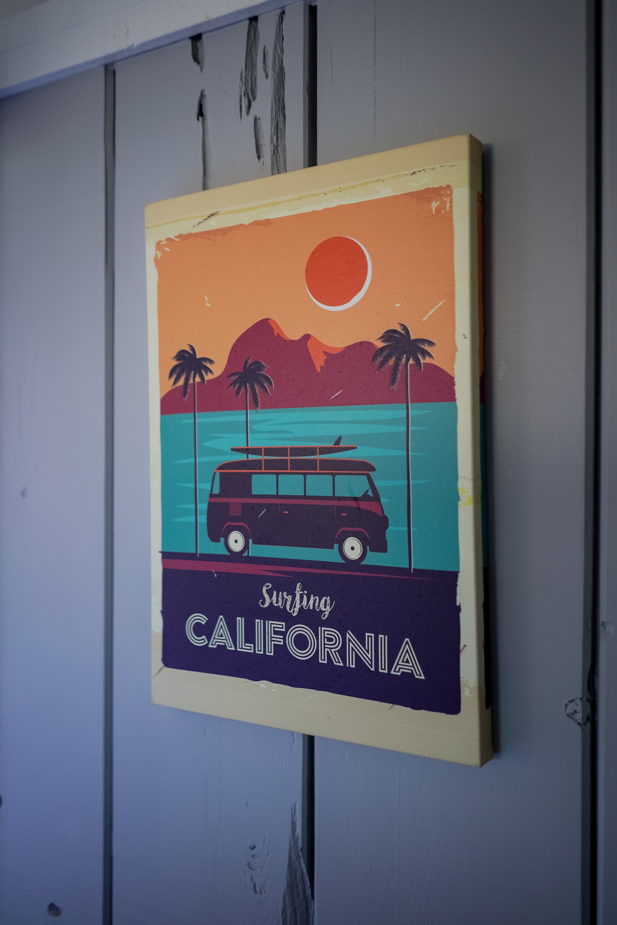 Close-up of a vintage-style 'サーフィン' art print featuring a surf van and palm trees against a sunset background.